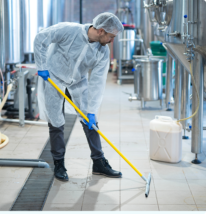 Man in coverall suit and hairnet, cleaning the floor of a warehouse in Nashville