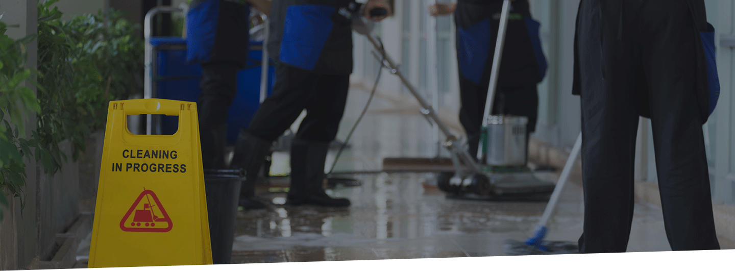 Cropped image of commercial cleaners working in facility with yellow cleaning sign.